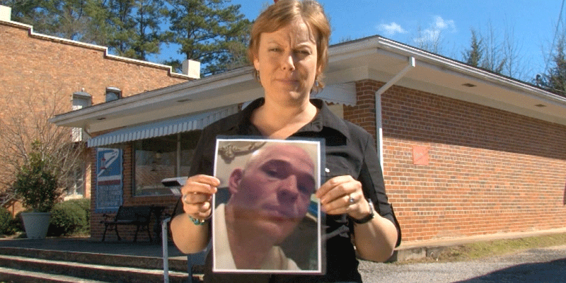 A woman holding a picture of a bald man